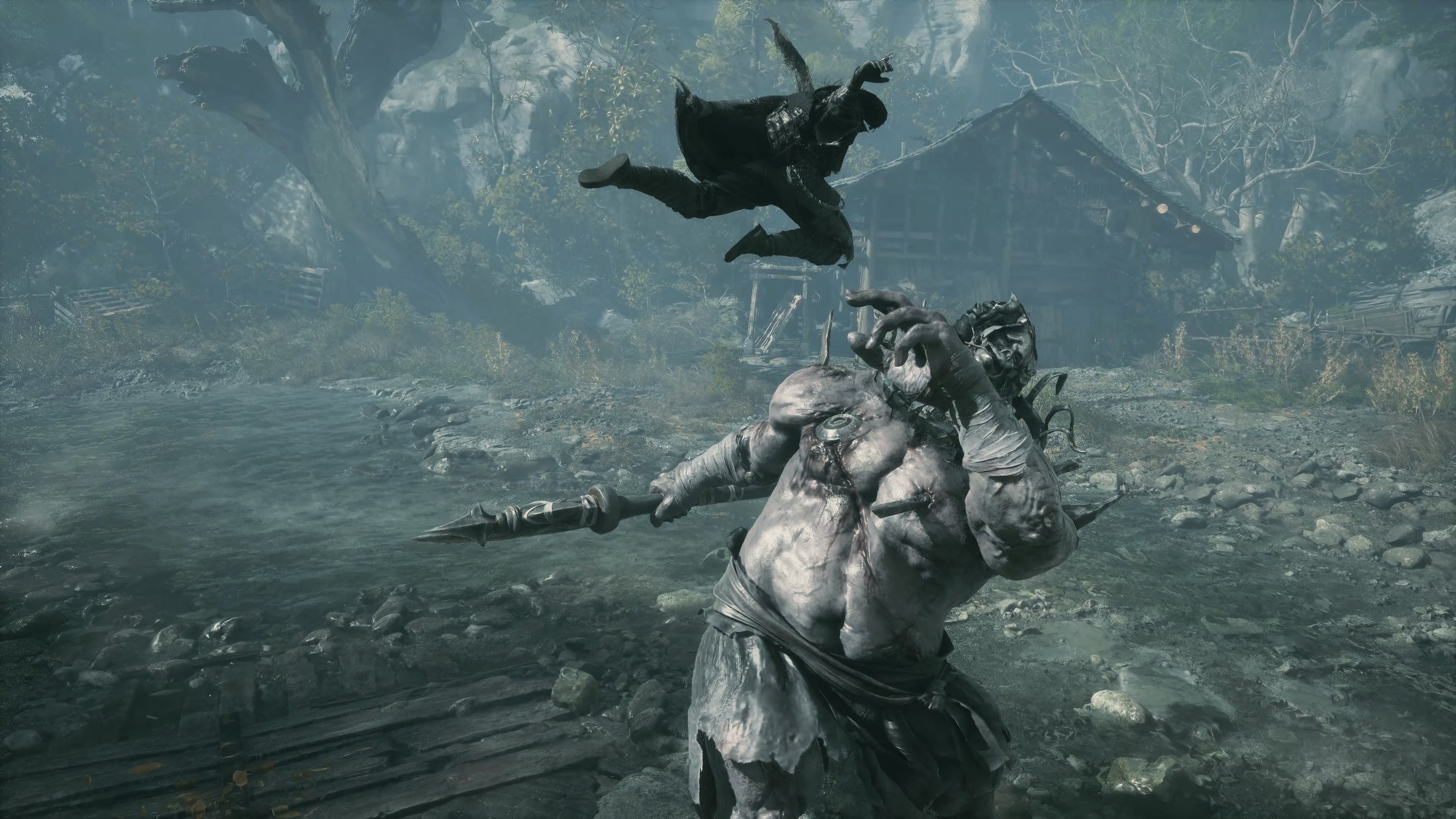 A grey-skinned spear fighter on a misty riverbank with a body thrown clear of the water behind him.